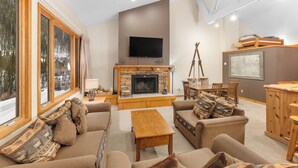 Una sala de estar acogedora con chimenea, asientos cómodos, televisión y un ventanal con vistas al exterior.