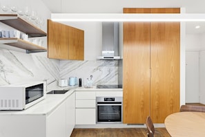 Une cuisine moderne dotée d’appareils électroménagers intégrés, de meubles en bois et d’un dosseret en marbre.