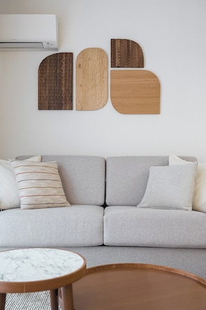 A modern living room with a grey sofa, a wooden coffee table, and a wall-mounted abstract art piece. - Historic Porto Flat | Central Porto (Porto)
