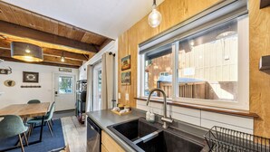 Eine moderne Küche mit Holzelementen, einem großen Fenster und einem Essbereich mit Tisch und Stühlen.