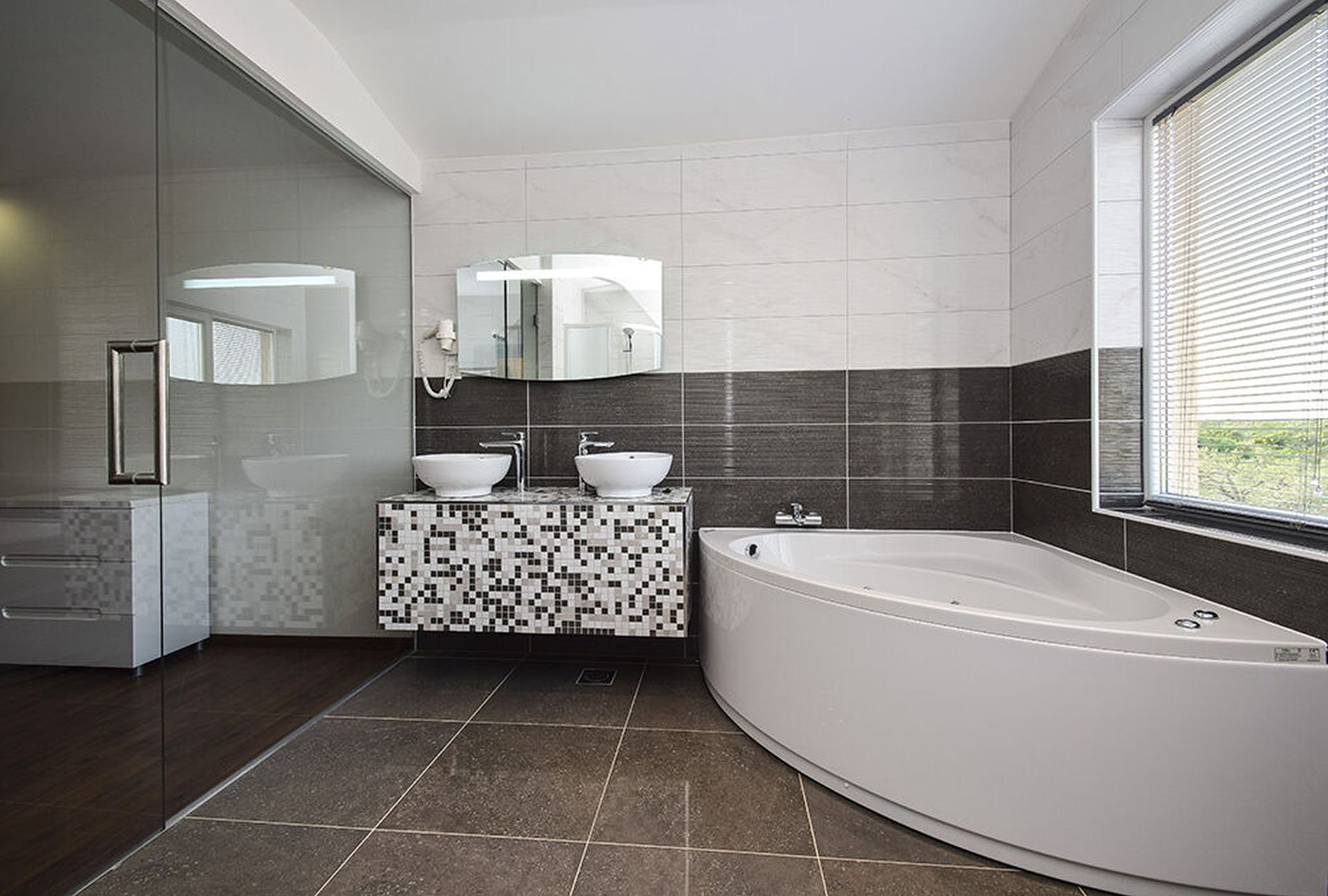 A modern bathroom with a freestanding bathtub, two sinks, and a large mirror above the vanity.