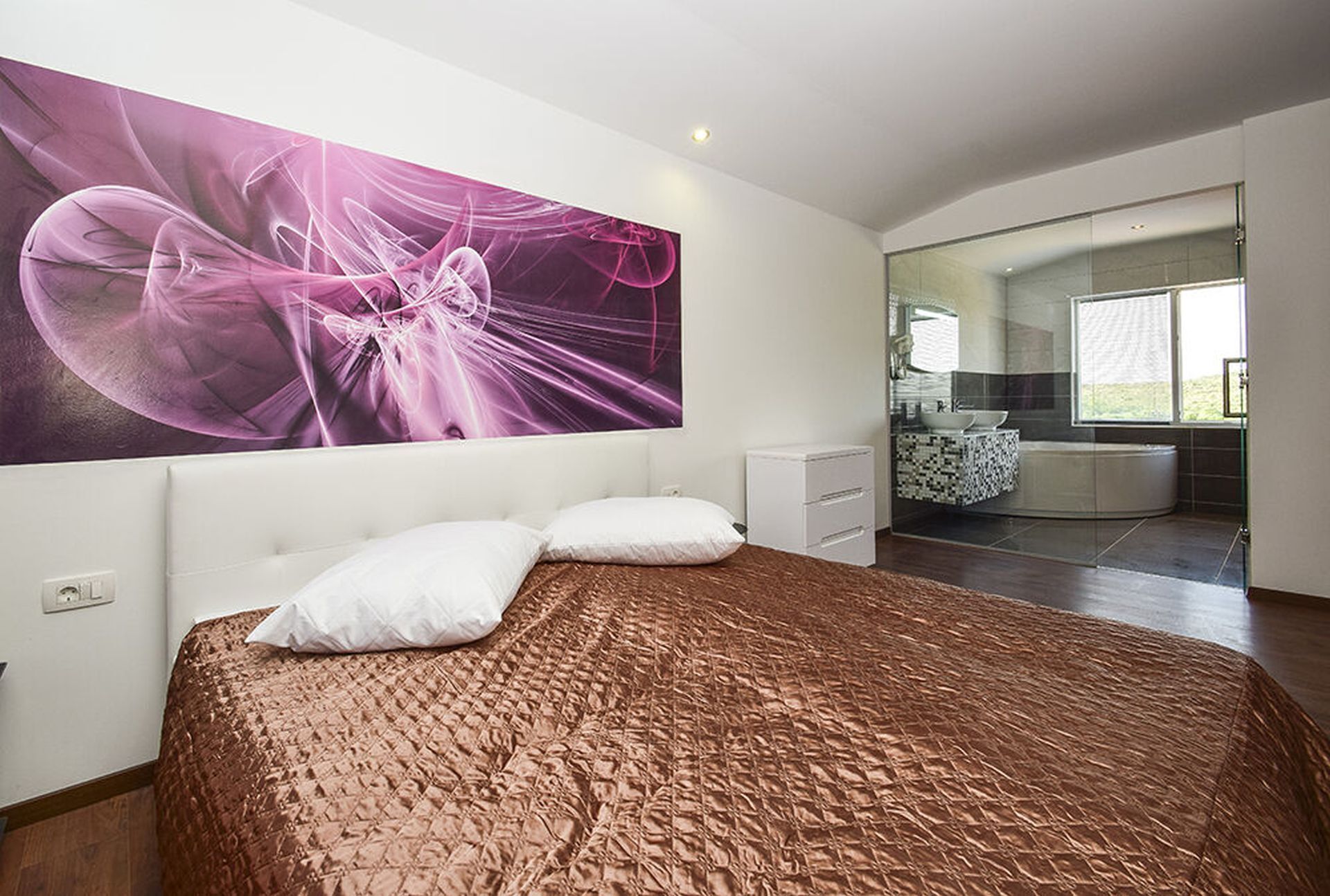 Un dormitorio moderno con una cama grande, un baño con bañera y vistas al exterior.
