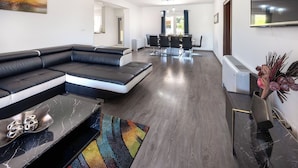 A modern living room with a sectional sofa, a dining area with a table and chairs, and a large mirror on the wall. - Villa Julija (Vodice)