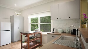 Una cocina moderna con salpicadero de mármol, horno empotrado y ventana con vistas a la vegetación.
