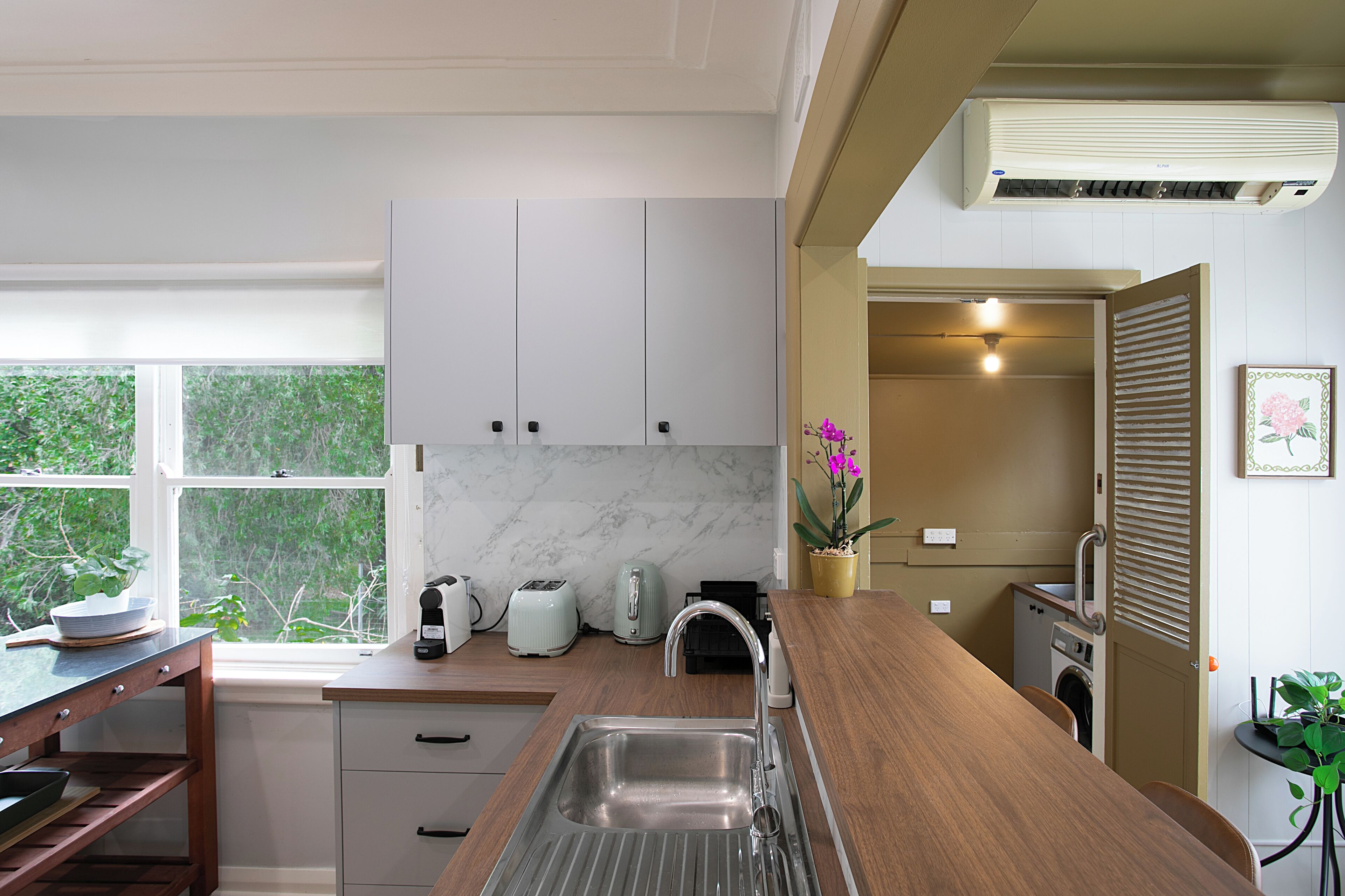 Een moderne keuken met witte kastjes, een marmeren spatwand en een houten aanrecht.