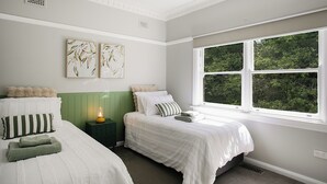 Un dormitorio con dos camas, una ventana con vistas a zonas verdes y obras de arte en la pared.