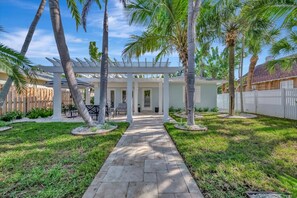 A pathway leading to a covered patio area with palm trees and a white fence. - Snowbirds in Luxury 60 Second Walk to the Beach (St. Pete Beach)