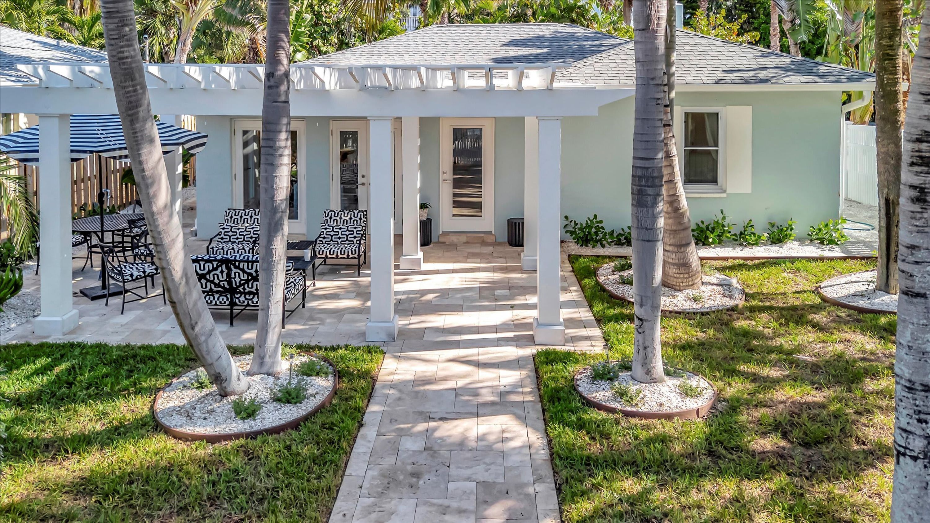 Un patio techado con mobiliario exterior y palmeras.