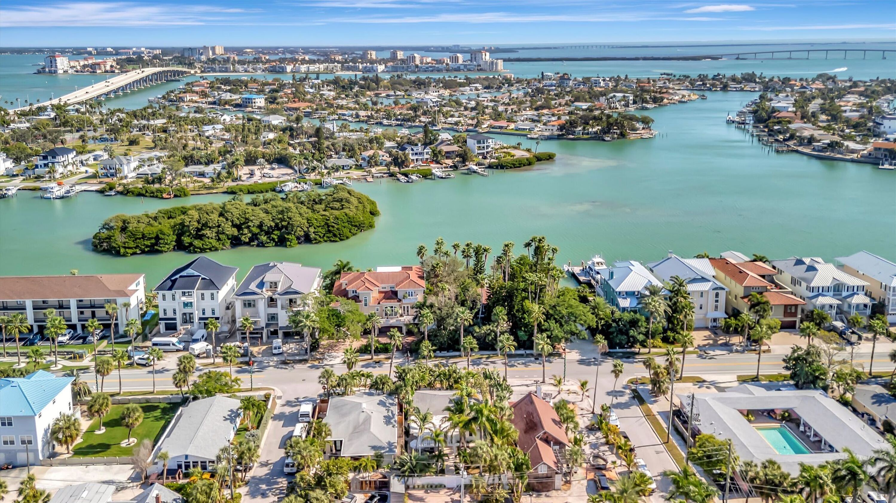 Zona residencial costera con un puerto deportivo, casas y un puente al fondo.
