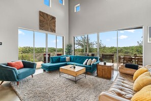 A spacious living room with a large sectional sofa, a coffee table, and a leather couch. - Luxury 4BR Hilltop Retreat With Scenic Views (Dripping Springs)