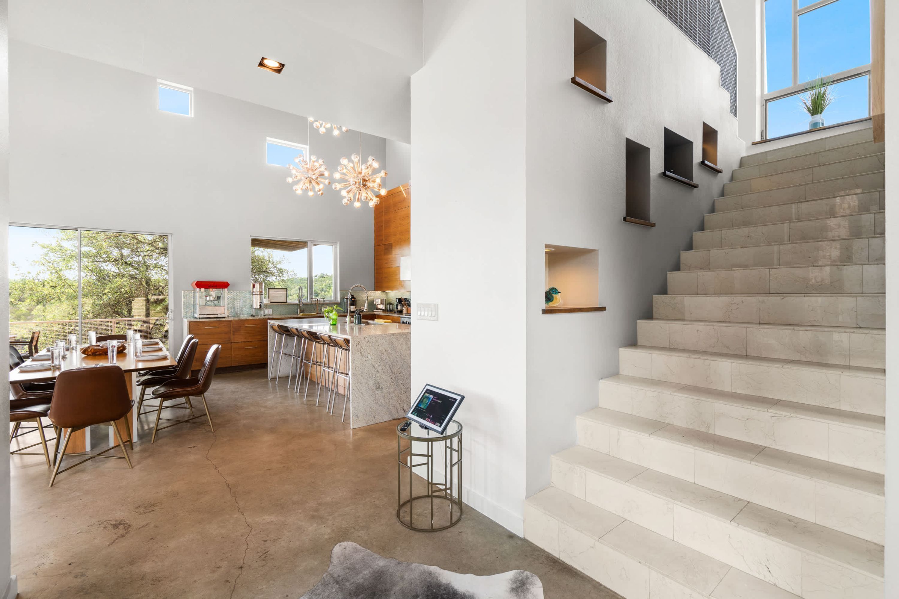 Un grand espace de vie comprenant une salle à manger avec table et chaises, une cuisine et un escalier.