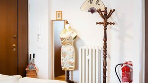 A living room with a sofa, a hanging lamp, a radiator, a wooden coat stand, and a fire extinguisher. - Casa Romitino Modern and Spacious Apartment (Florence)