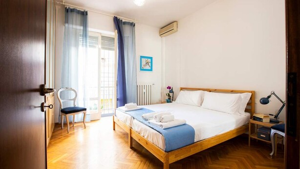 A bedroom with a wooden bed, a chair, a desk, and a window with curtains. - Casa Romitino Modern and Spacious Apartment (Florence)