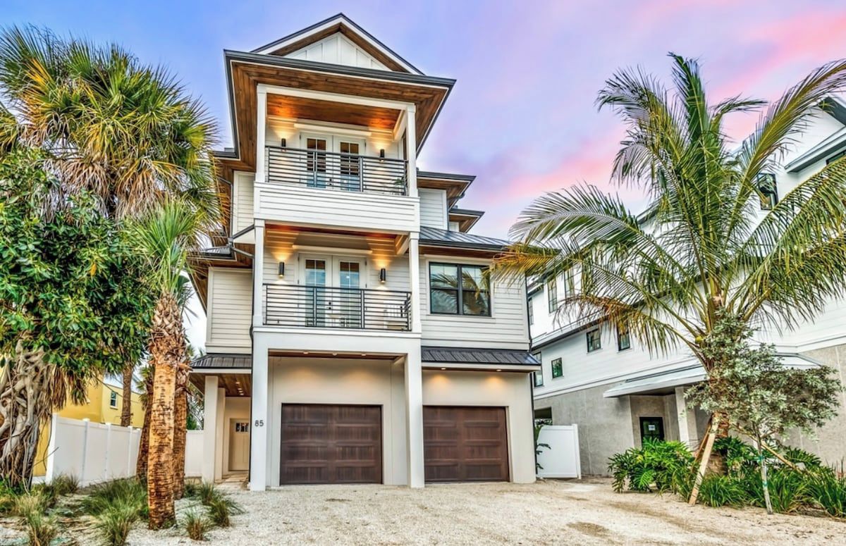 A multi-story residential building with a garage, surrounded by palm trees.
