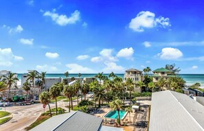 A resort with a pool, palm trees, and a view of the ocean. - New! Beach House with heated pool/spa water slide! (Siesta Key)