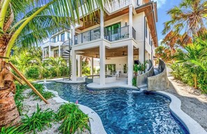 A modern multi-story house with a swimming pool, surrounded by tropical vegetation. - New! Beach House with heated pool/spa water slide! (Siesta Key)