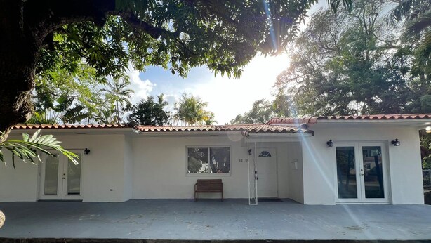 Un bâtiment à deux étages, avec un toit recouvert de tuiles, une porte d’entrée et un banc à l’extérieur.