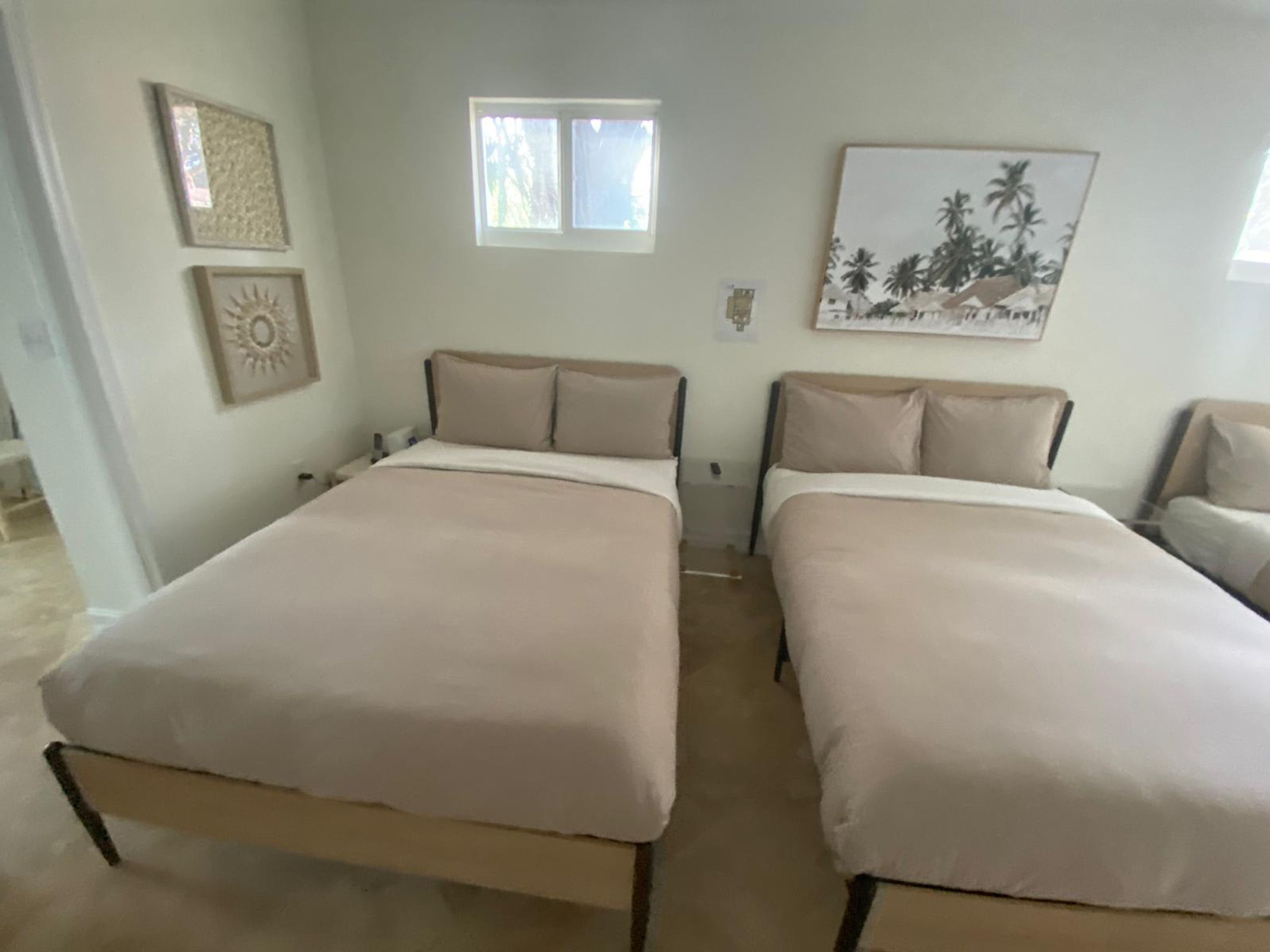 A room with two beds, a window, and wall art.