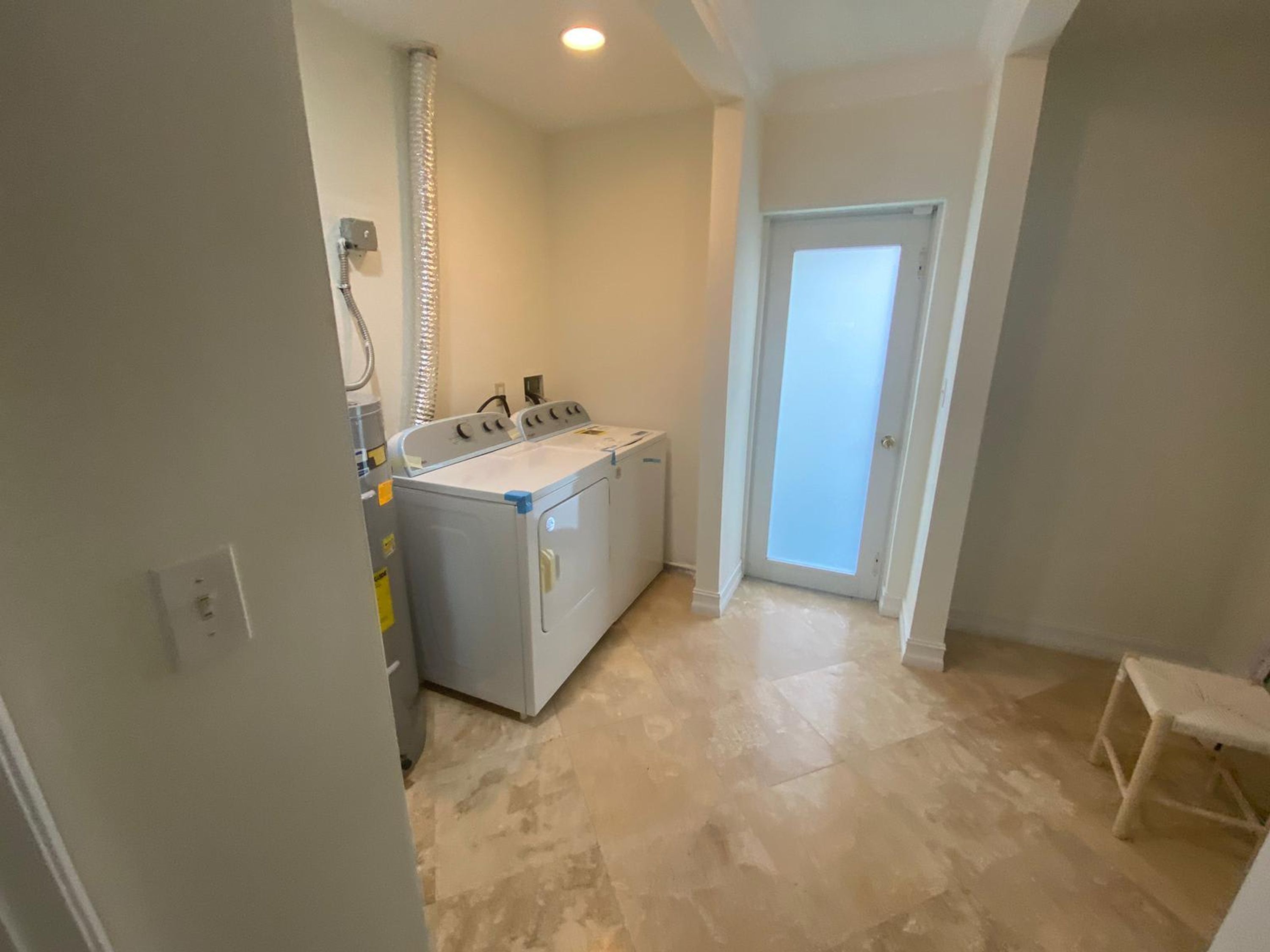 A laundry room with a washing machine and dryer, a vent, and a door leading to another room.