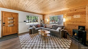 A cozy living room with a wooden ceiling, a sofa, a coffee table, and a fireplace. - 3300 Cape Horn 3 Bedroom Home (South Lake Tahoe)