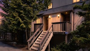 A two-story building with a wooden staircase leading to the entrance, a porch with a railing, and a street sign indicating the address. - Pocono Paradise Ultimate Camelback Getaway 4 Bedroom Townhouse (Tannersville)