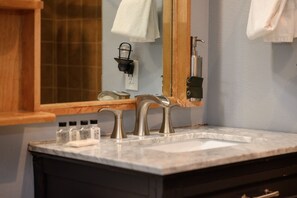 A bathroom with a marble sink, a wooden cabinet, and a mirror. - Premium Unit 1100 - One Bedroom - Zephyr Mountain Lodge 1 Condo (Winter Park)