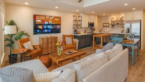 A modern living room with a sofa, coffee table, and a TV mounted on the wall. - Penthouse Beachfront Views Renovated 4 Bedroom Condo (South Padre Island)