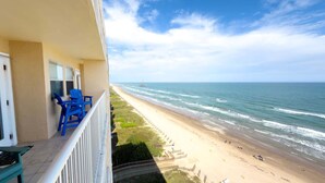 A balcony with blue chairs overlooking a beach with waves and a distant ship. - Penthouse Beachfront Views Renovated 4 Bedroom Condo (South Padre Island)