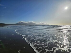 A beach with waves, a mountain in the background, and a clear sky. - Wendon Holidays - Seaview (Dinas Dinlle)