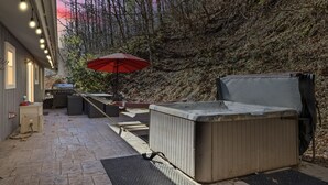 Eine Terrasse mit Whirlpool, Sitzgelegenheit und einem roten Sonnenschirm.