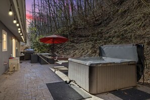 A patio area with a hot tub, outdoor seating, and a red umbrella. - Smokin' Blue Villa 3 Bedroom Home (Gatlinburg)