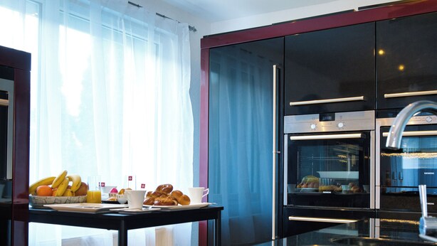 A modern kitchen with a breakfast table set with fruits, pastries, and coffee. - Modern Station Apartment Möhlin (Möhlin)