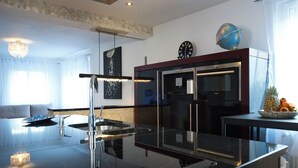 A modern kitchen with a black countertop, stainless steel appliances, and a globe on the wall. - Modern Station Apartment Möhlin (Möhlin)