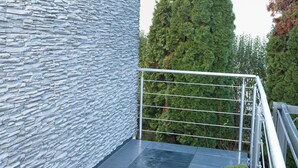 A balcony with a stone wall, metal railing, and a tiled floor. - Modern Station Apartment Möhlin (Möhlin)