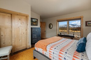 A bedroom with a bed, a window with a mountain view, a wooden wardrobe, and a desk. - Eagles Wings is a gorgeous 3-bedroom property with incredible mountain views! (Pray)