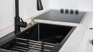 Una cuina moderna amb un aixeta negra, una placa de cocció integrada i una prestatgeria sobre l'aigüera.