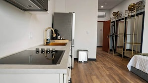 A compact hotel room with a kitchenette, a bed, and a wardrobe with mirrors.