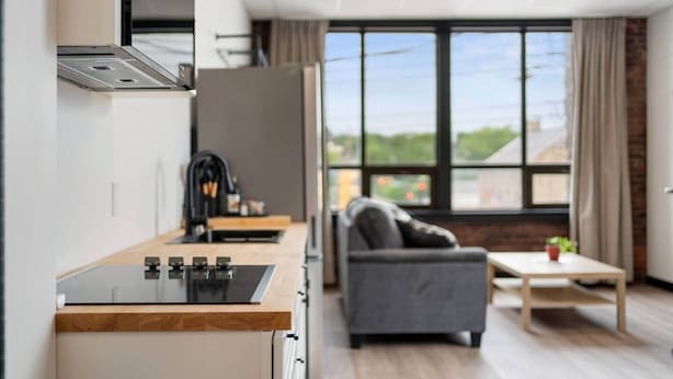 A modern kitchen with a built-in stove and a dining area with a sofa and table.