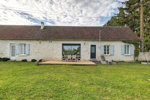 Una casa con tejado de tejas, puerta principal y un pequeño patio con mesa y sillas.