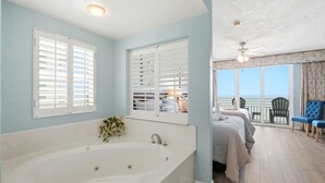 Une chambre dotée d’une grande baignoire, de deux lits, d’un balcon avec vue et d’un ventilateur de plafond.