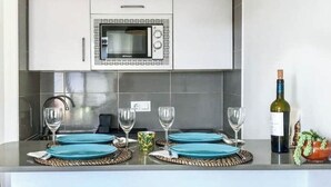 A kitchen with a built-in microwave, a wine bottle, and a potted plant. - A seaside retreat with swimming pool (Ciutadella)