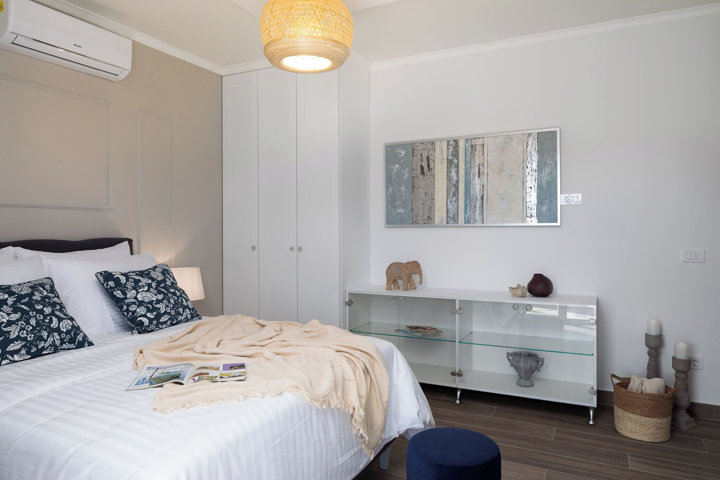 Un dormitorio con cama, armario blanco, estanterías de vidrio y un cuadro colgado en la pared.