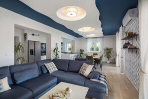 A modern living room with a dark blue sectional sofa, a white coffee table, and recessed ceiling lights. - Villa Peregrine (Pakostane)