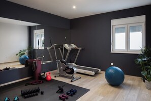 Une salle de sport équipée de matériel d’exercice, d’un tapis de course et d’un grand ballon bleu pour faire de l’exercice.