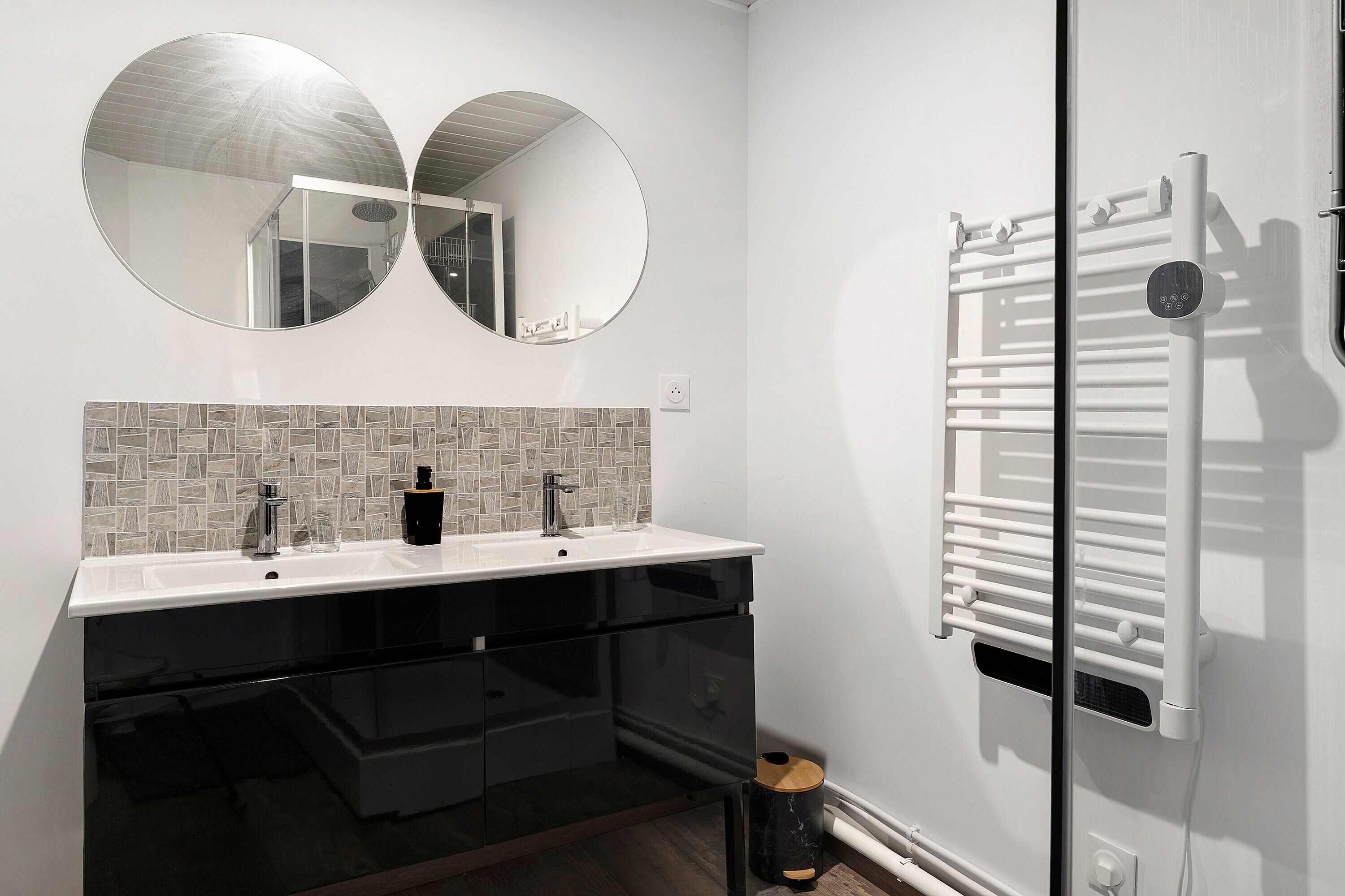 Een moderne badkamer met twee wastafels, een spiegel en een handdoekrek.
