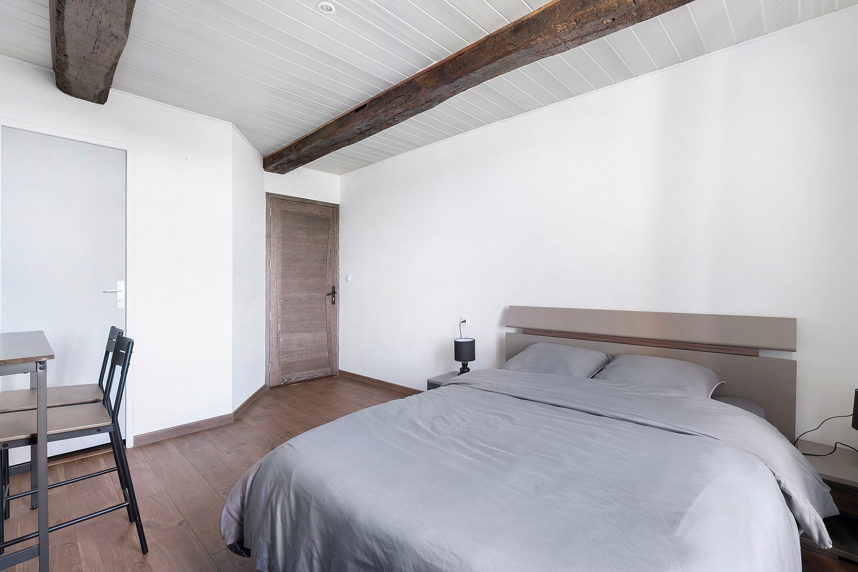 A bedroom with a bed, a desk, and a chair.