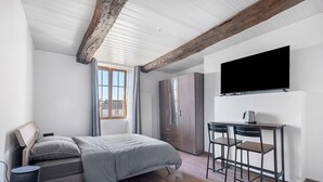 A modern bedroom with a bed, a desk with two chairs, a TV, and a window with curtains. - The Cocon Room with Wi-Fi (Frossay)