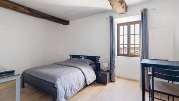 A bedroom with a bed, bedside table, and a desk.