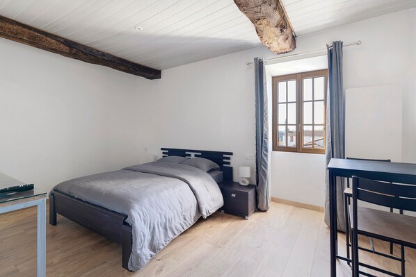 A bedroom with a bed, bedside table, and a desk.