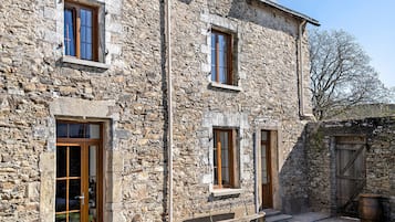 A stone building with multiple windows, a wooden door, and a bench outside.
